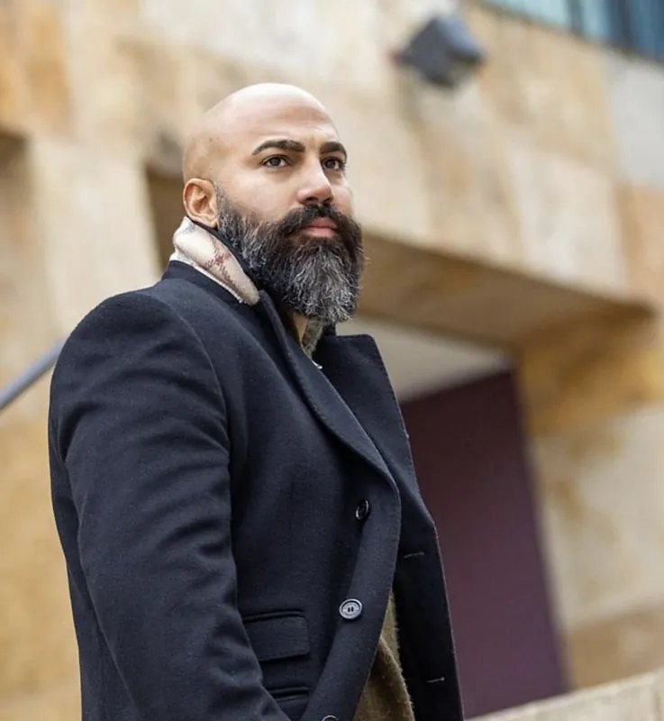 Ömer Kaya im dunklen Mantel mit Schal und grauem Bart in Bonn