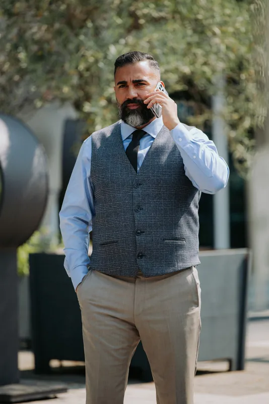 Ömer Kaya in karierter Weste und hellblauem Hemd beim Telefonieren